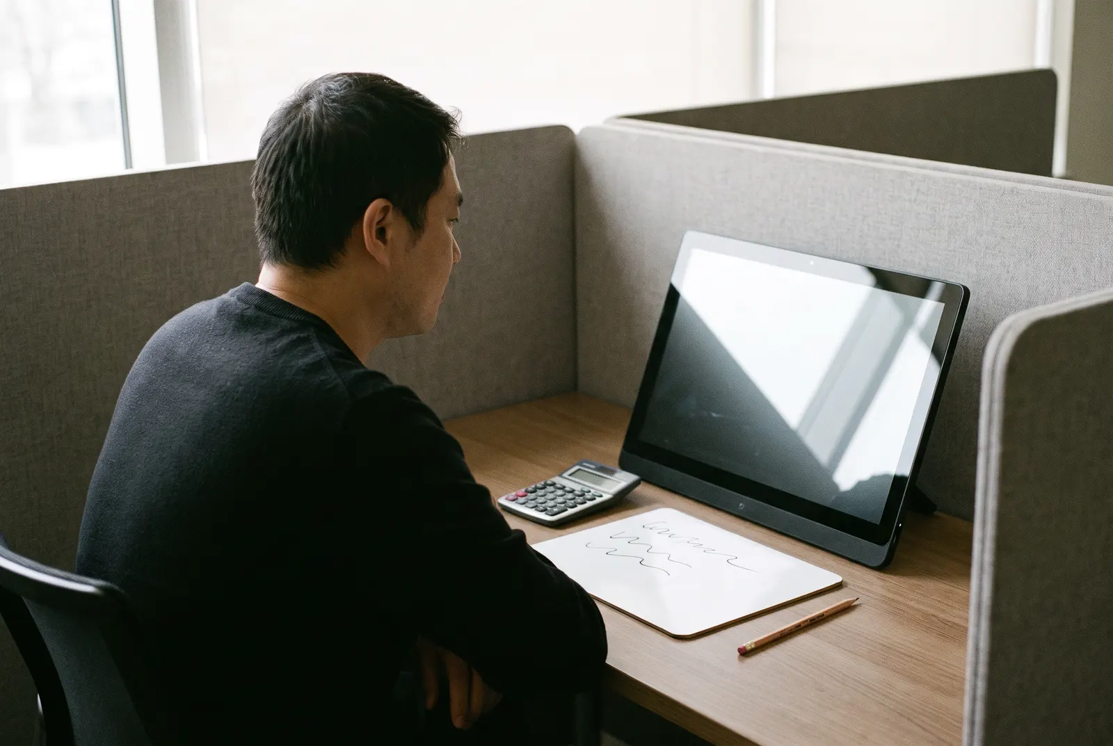 Adult at a testing center desk with a calculator and pencil, preparing for the CPA exam